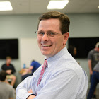 A person wearing glasses and a tie Description automatically generated